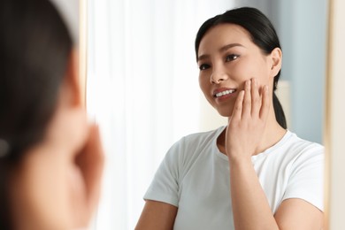 Portrait of beautiful woman near mirror indoors