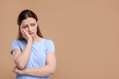 Photo of Portrait of sad woman on beige background, space for text