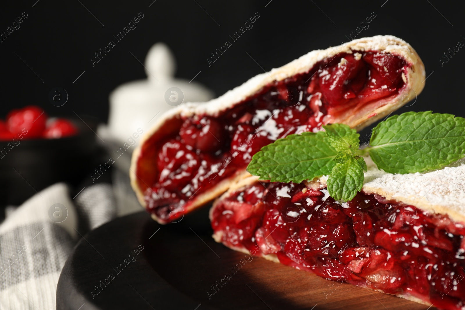 Photo of Delicious strudel with cherries, powdered sugar and mint on table, closeup