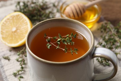 Cup of aromatic herbal tea with thyme on table, closeup