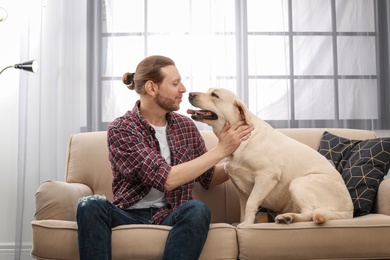 Photo of Adorable yellow labrador retriever with owner on couch indoors