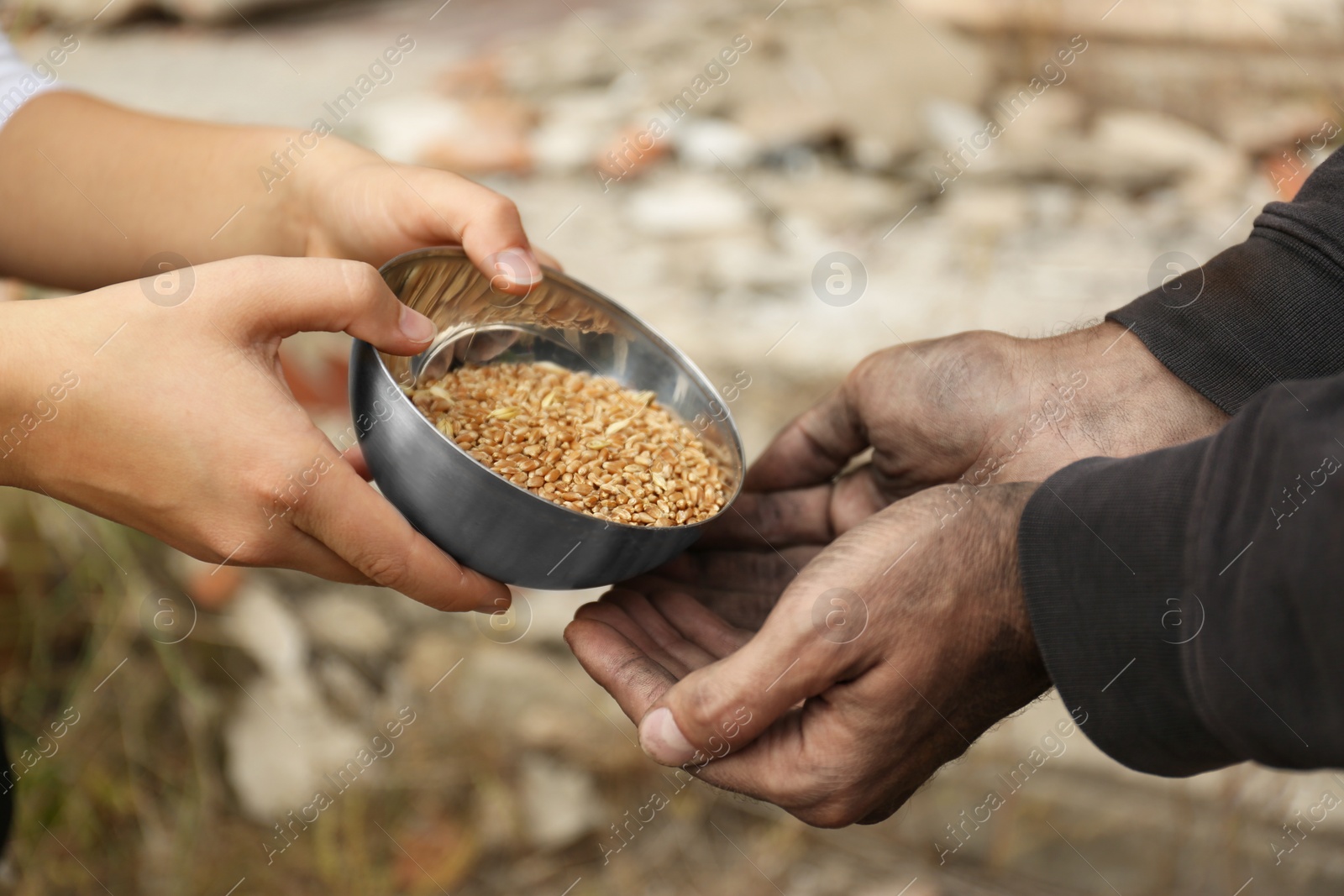 Photo of Woman giving poor homeless man bowl of wheat outdoors, closeup