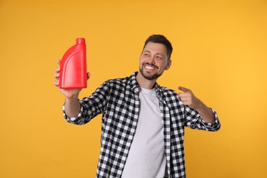 Photo of Man pointing at red container of motor oil on orange background