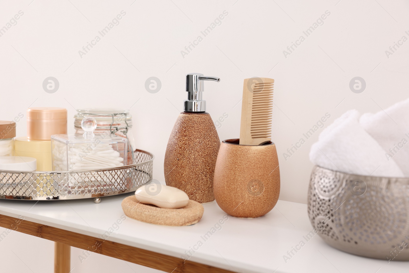 Photo of Different bath accessories and personal care products on table near white wall