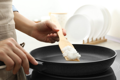 Photo of Woman cooking with coconut oil on induction stove, closeup