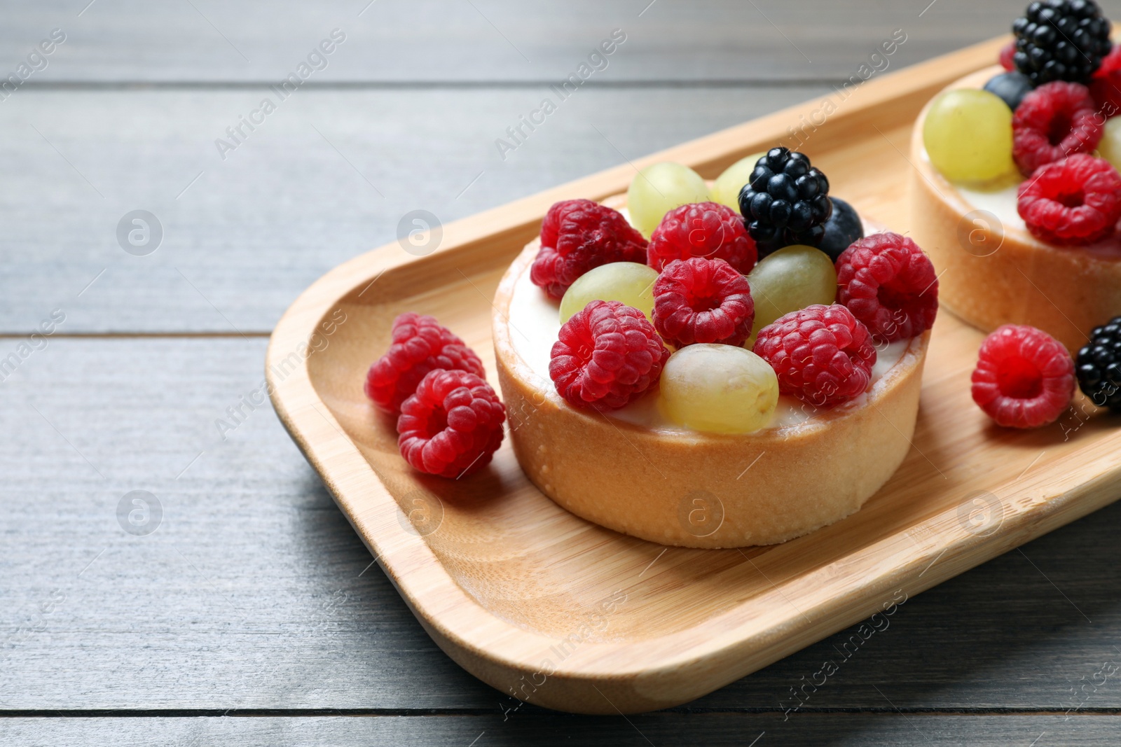 Photo of Delicious tartlets with berries on wooden table, closeup