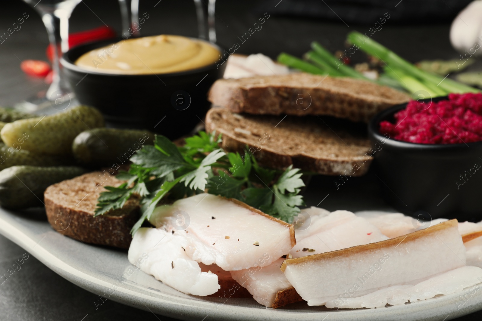 Photo of Tasty salt pork with rye bread and sauces served on table, closeup