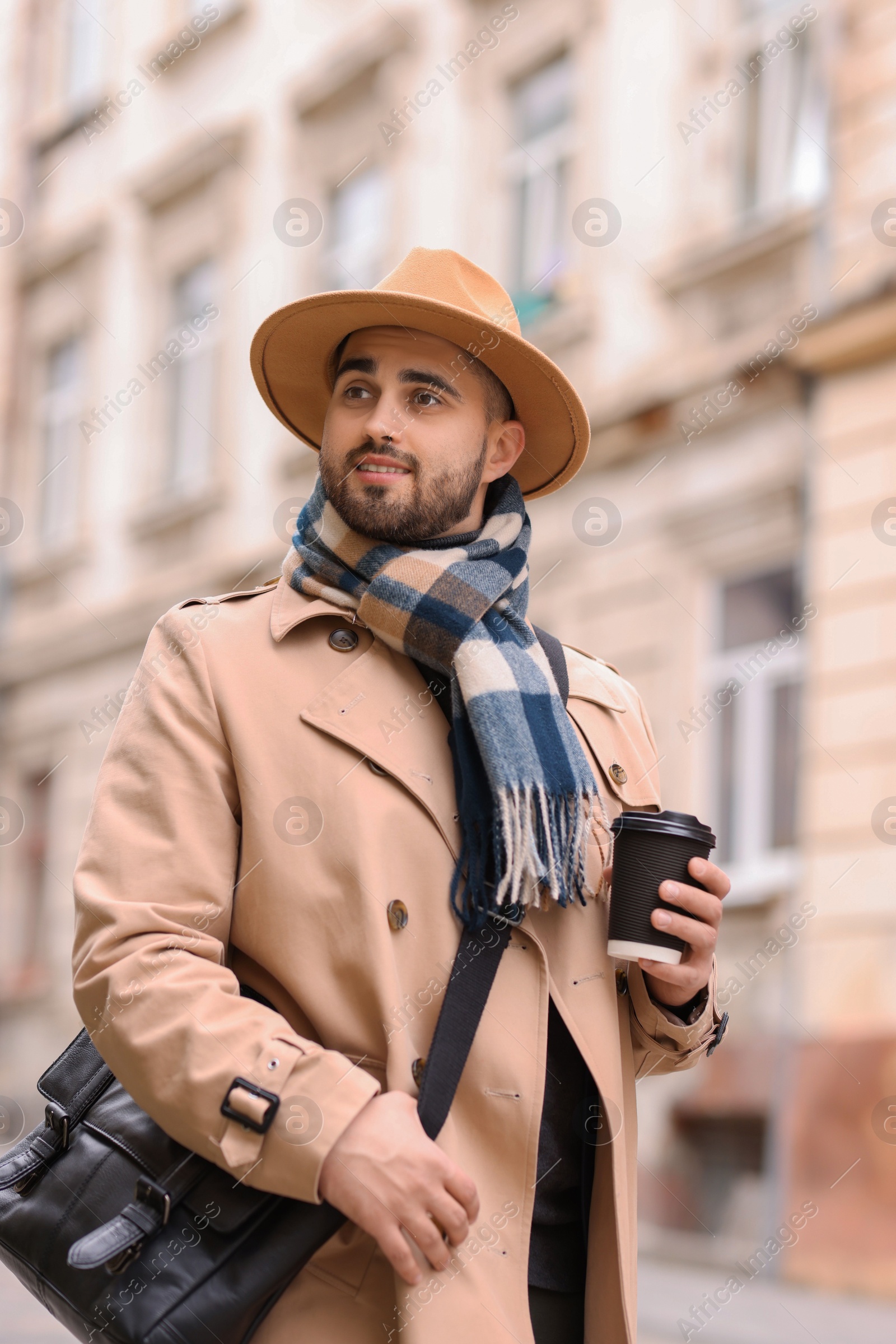 Photo of Smiling man in warm scarf with paper cup outdoors