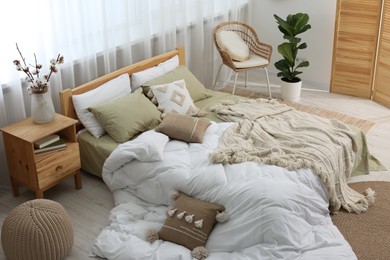 Photo of Large comfortable bed with soft pillows, duvet and blanket in room. Home textile