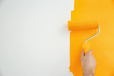 Photo of Man painting white wall with yellow dye, closeup. Interior renovation