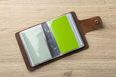 Leather business card holder with blank cards on wooden table, top view