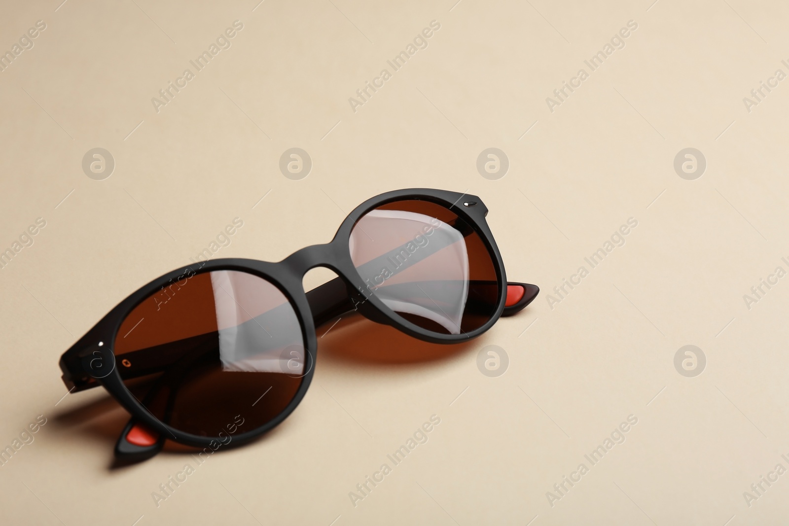 Photo of Stylish sunglasses on beige background. Fashionable accessory