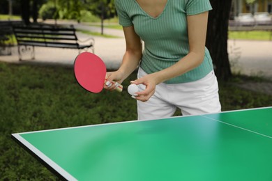 Photo of Young woman playing ping pong in park, closeup