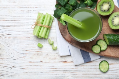 Photo of Glass of celery juice and fresh ingredients on white wooden table, flat lay. Space for text