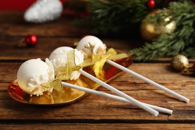 Photo of Delicious Christmas themed cake pops on wooden table