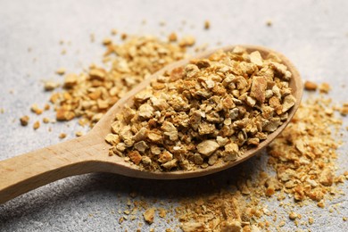 Photo of Spoon with dried orange zest seasoning on light grey table, closeup