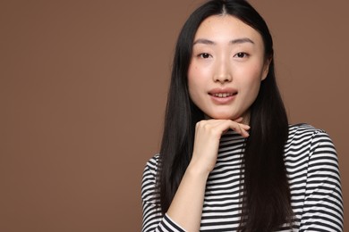 Portrait of smiling woman on brown background. Space for text