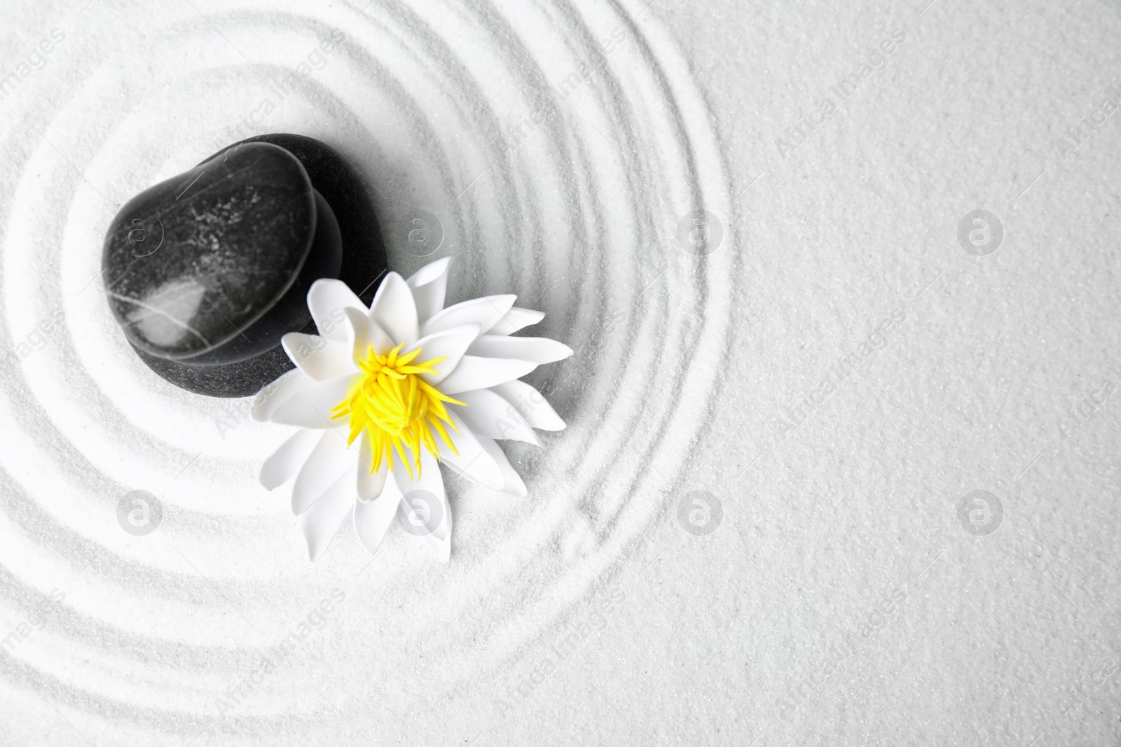 Photo of Zen garden. Beautiful lotus flower and stones on white sand, flat lay