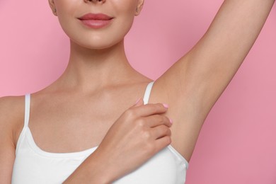 Young woman showing smooth skin after epilation on pink background, closeup