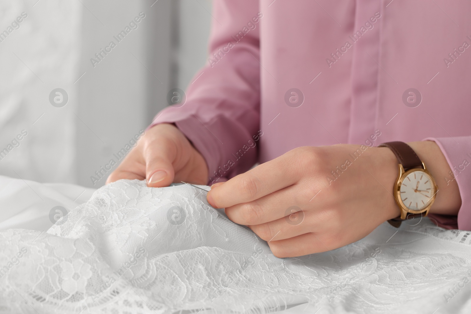 Photo of Dressmaker sewing wedding dress in atelier, closeup