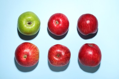 Ripe red and green apples on light blue background, flat lay