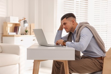 Photo of Man with poor posture using laptop at table indoors