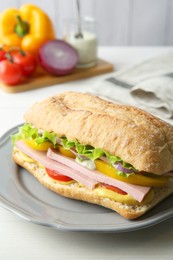 Photo of Tasty sandwich with boiled sausage, cheese and vegetables on white wooden table, closeup