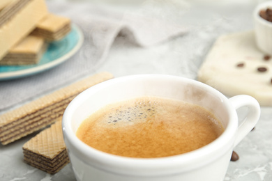 Delicious coffee and wafers for breakfast on grey marble table, closeup