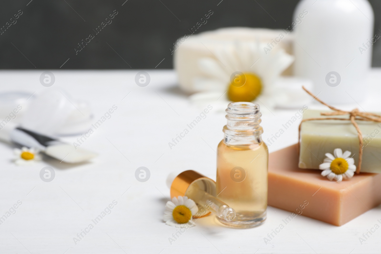 Photo of Composition with chamomile flowers and cosmetic products on white wooden table, space for text