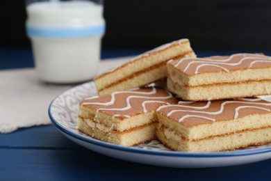 Tasty sponge cakes and milk on blue wooden table, closeup