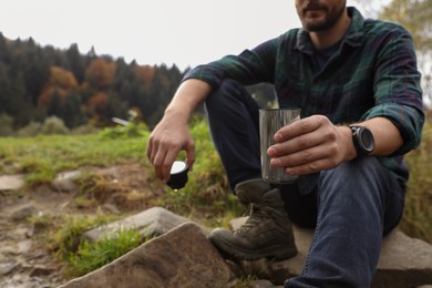 Man with thermo tumbler in nature, closeup. Space for text