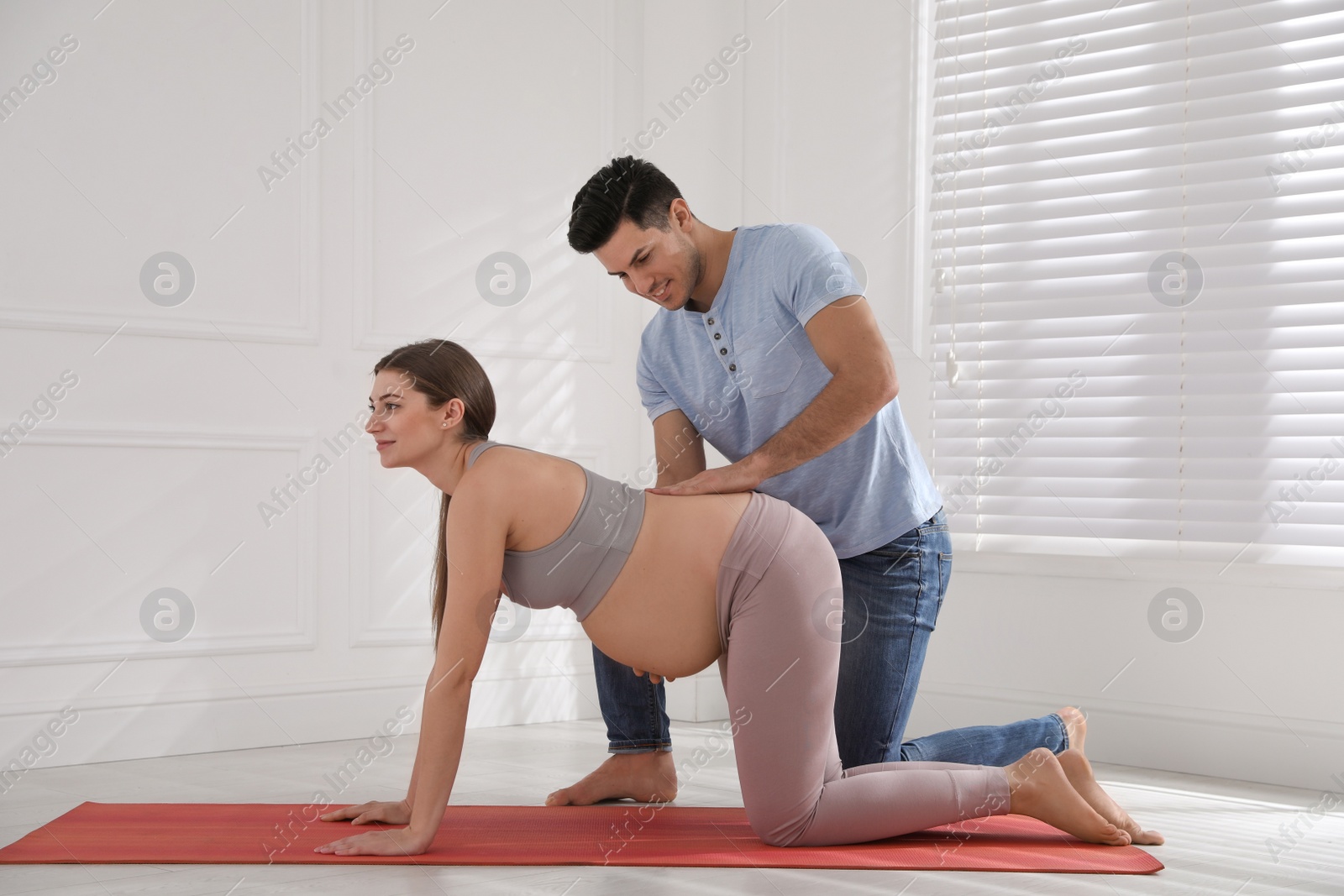 Photo of Husband massaging his pregnant wife in light room. Preparation for child birth