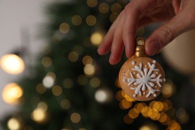 Photo of Woman holding Christmas macaron against blurred festive lights, closeup. Space for text