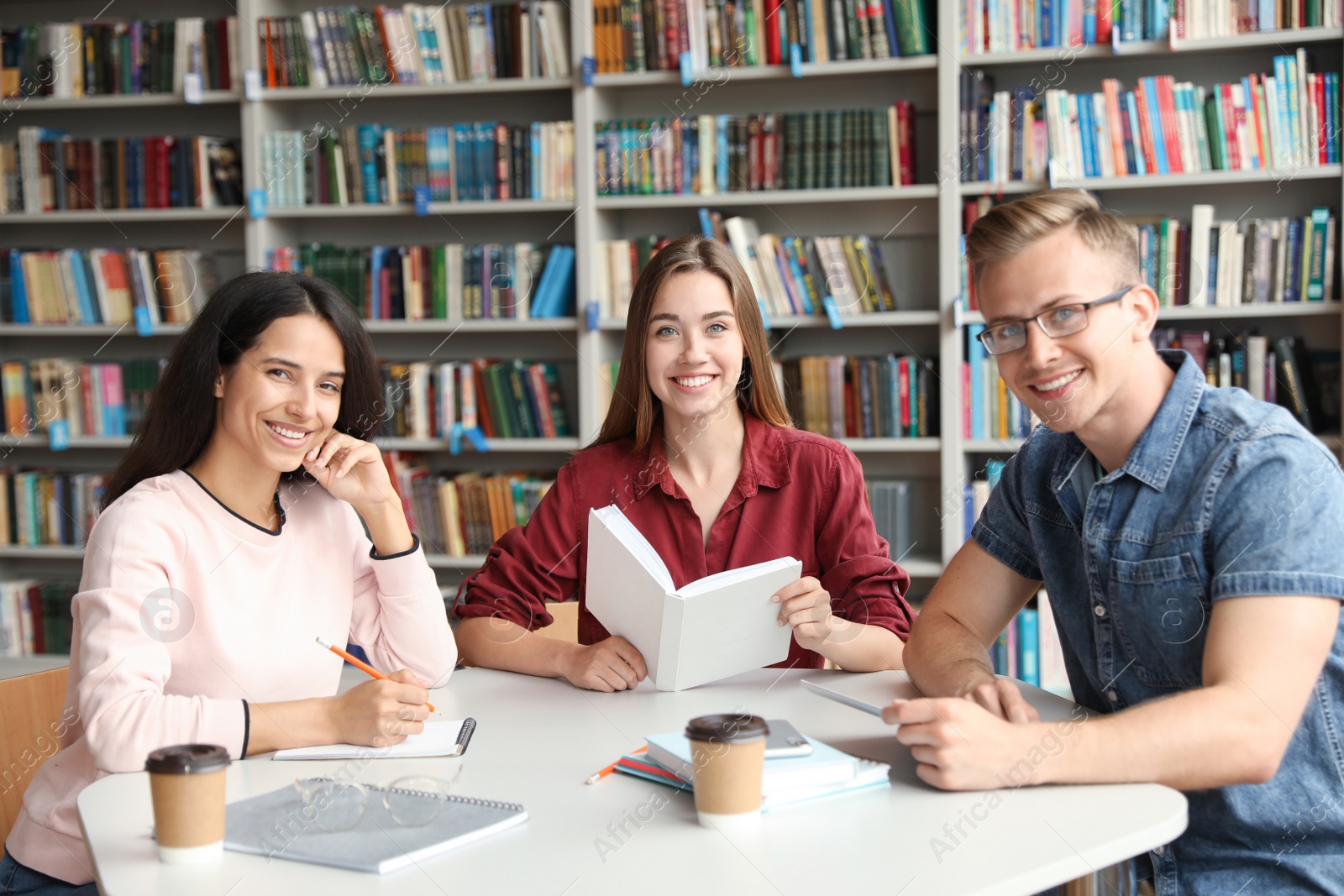 Photo of Young people discussing group project at table in library