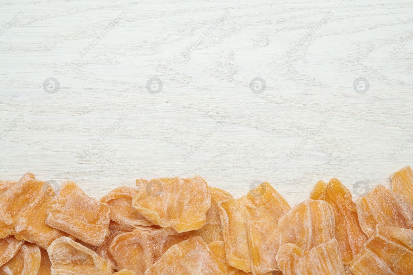 Photo of Delicious dried jackfruit slices on white wooden table, flat lay. Space for text