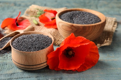 Photo of Wooden bowls of poppy seeds and flower on color table