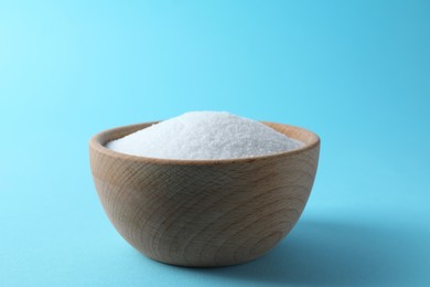 Organic white salt in bowl on light blue background