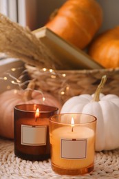 Scented candles and pumpkins on wicker mat indoors