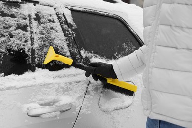 Photo of Man cleaning snow from car outdoors, closeup