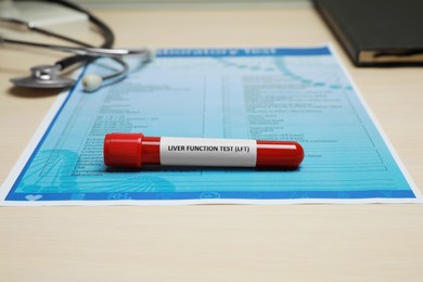 Photo of Liver Function Test. Tube with blood sample and laboratory form on wooden table