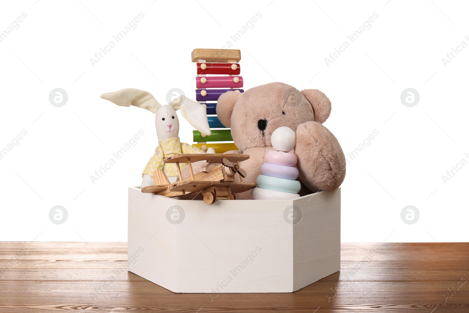 Photo of Set of different toys in box on wooden table against white background