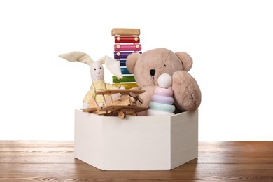 Set of different toys in box on wooden table against white background