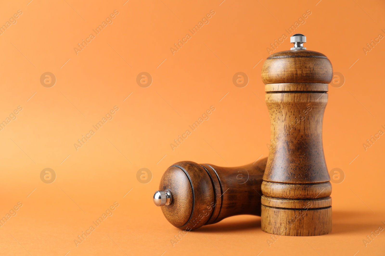 Photo of Wooden salt and pepper shakers on orange background. Space for text