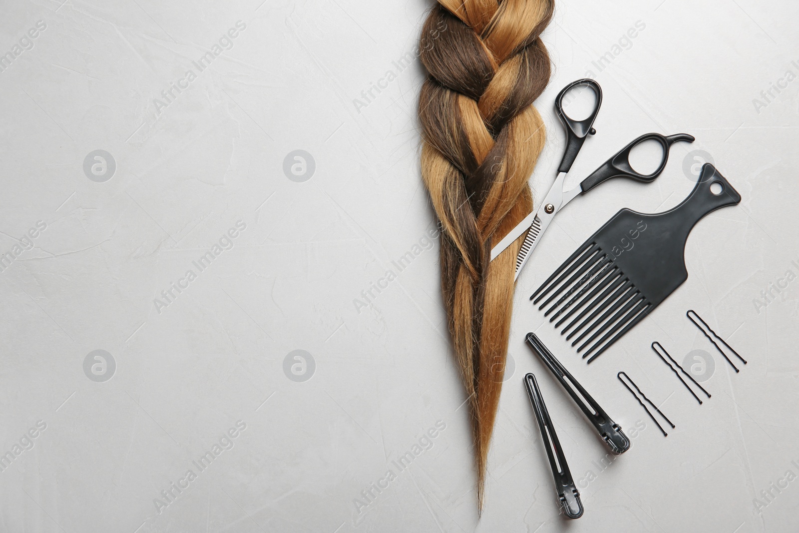 Photo of Flat lay composition with braid, hairdresser's tools and space for text on gray background