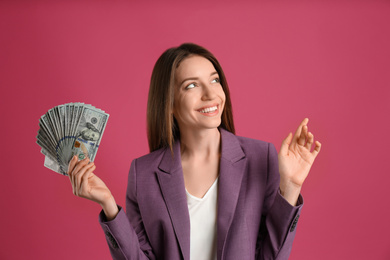 Happy young woman with cash money on pink background