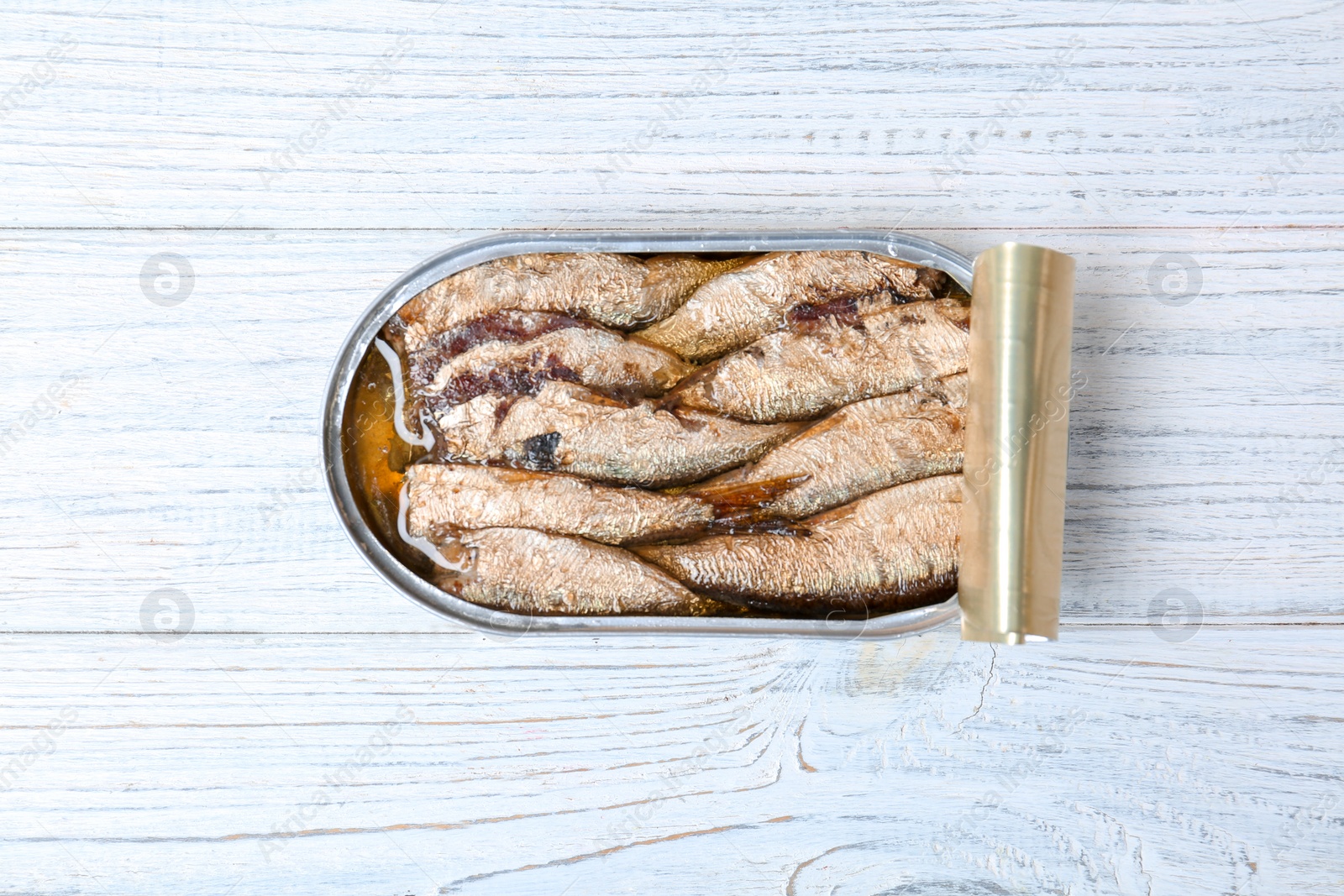 Photo of Tin can with conserved fish on wooden background, top view