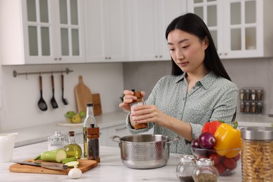 Beautiful woman cooking at countertop in kitchen