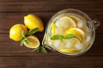 Photo of Glass jug with natural lemonade on wooden table, top view