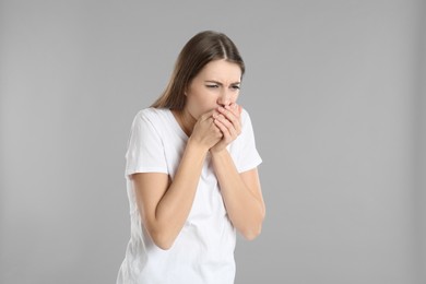 Woman suffering from nausea on grey background. Food poisoning