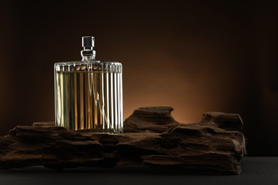 Photo of Luxury men`s perfume in bottle on table against brown background, space for text